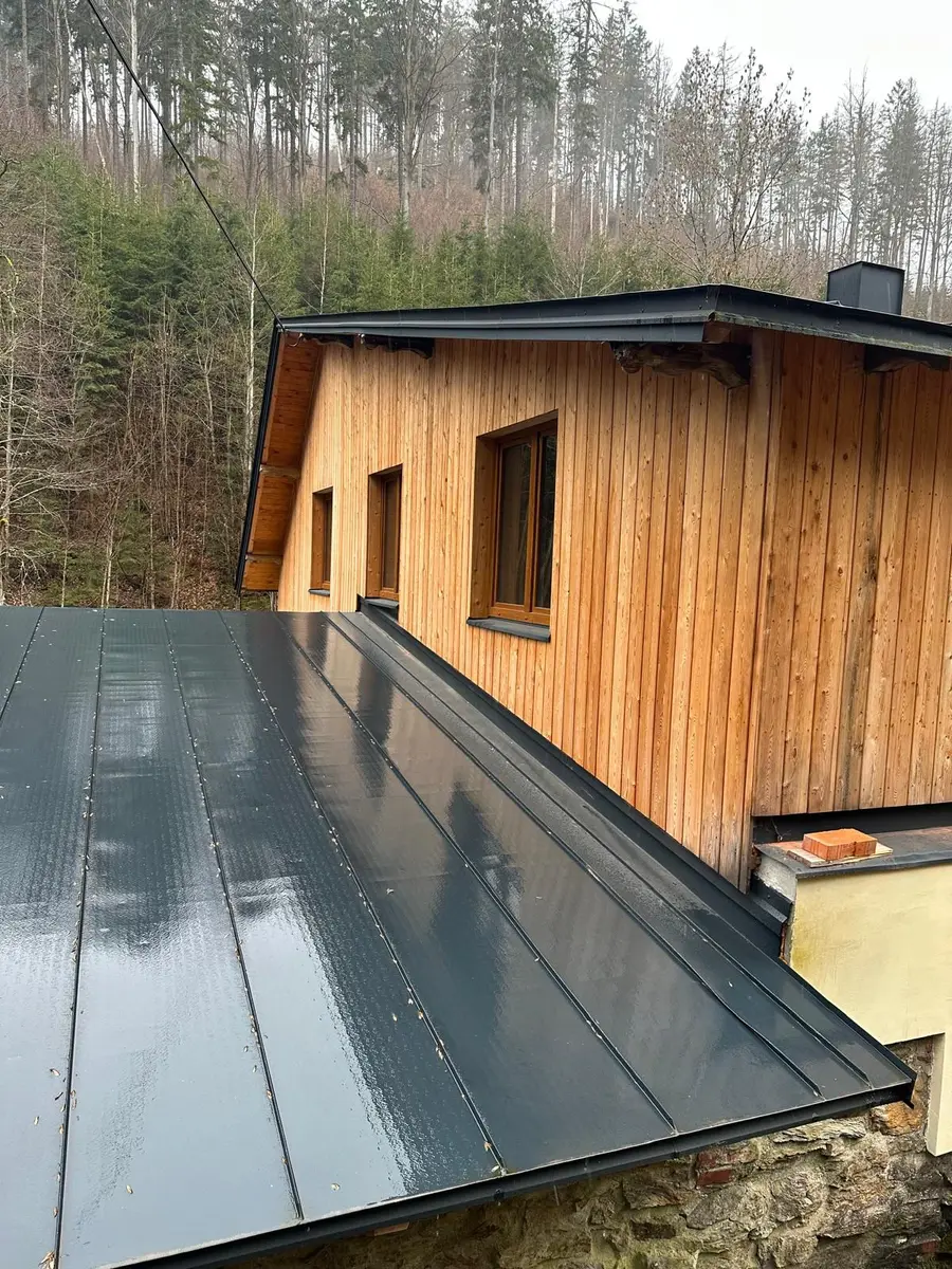 Detail plechové falcované střechy a dřevěného obkladu dokončené dřevostavby